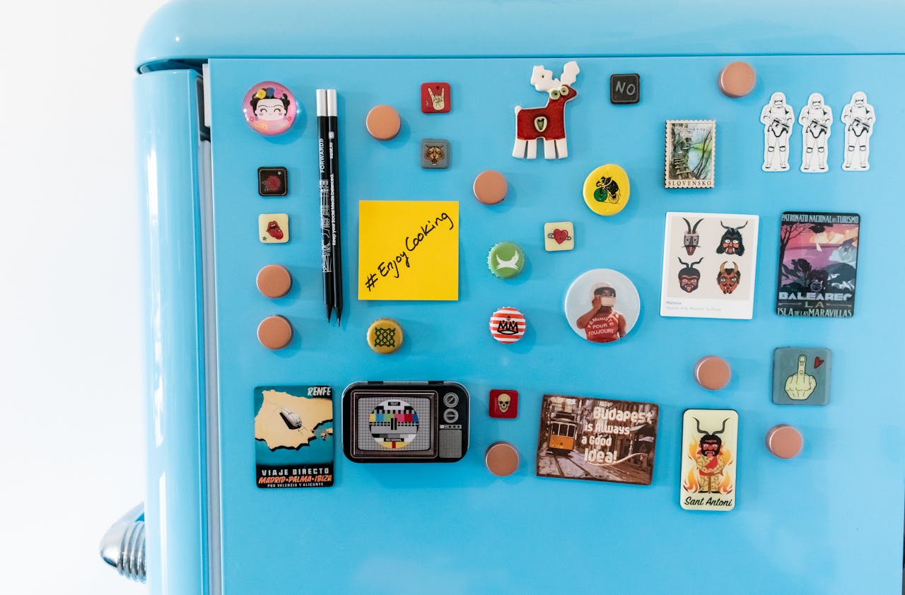 hero-img-02 Bright blue fridge adorned with fun travel magnets, sticky notes, and decorations.